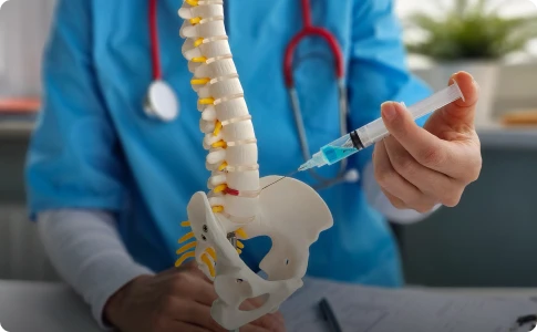 A doctor holds a syringe and a spine model, illustrating sympathetic nerve blocks